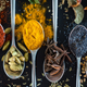 Aerial view of various spices piled on teaspoons